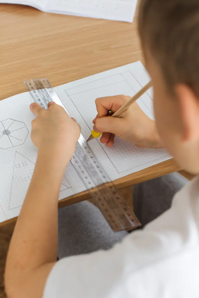 Lapsi tekee matematiikan tehtäviä vihkoon kynällä ja viivoittimella